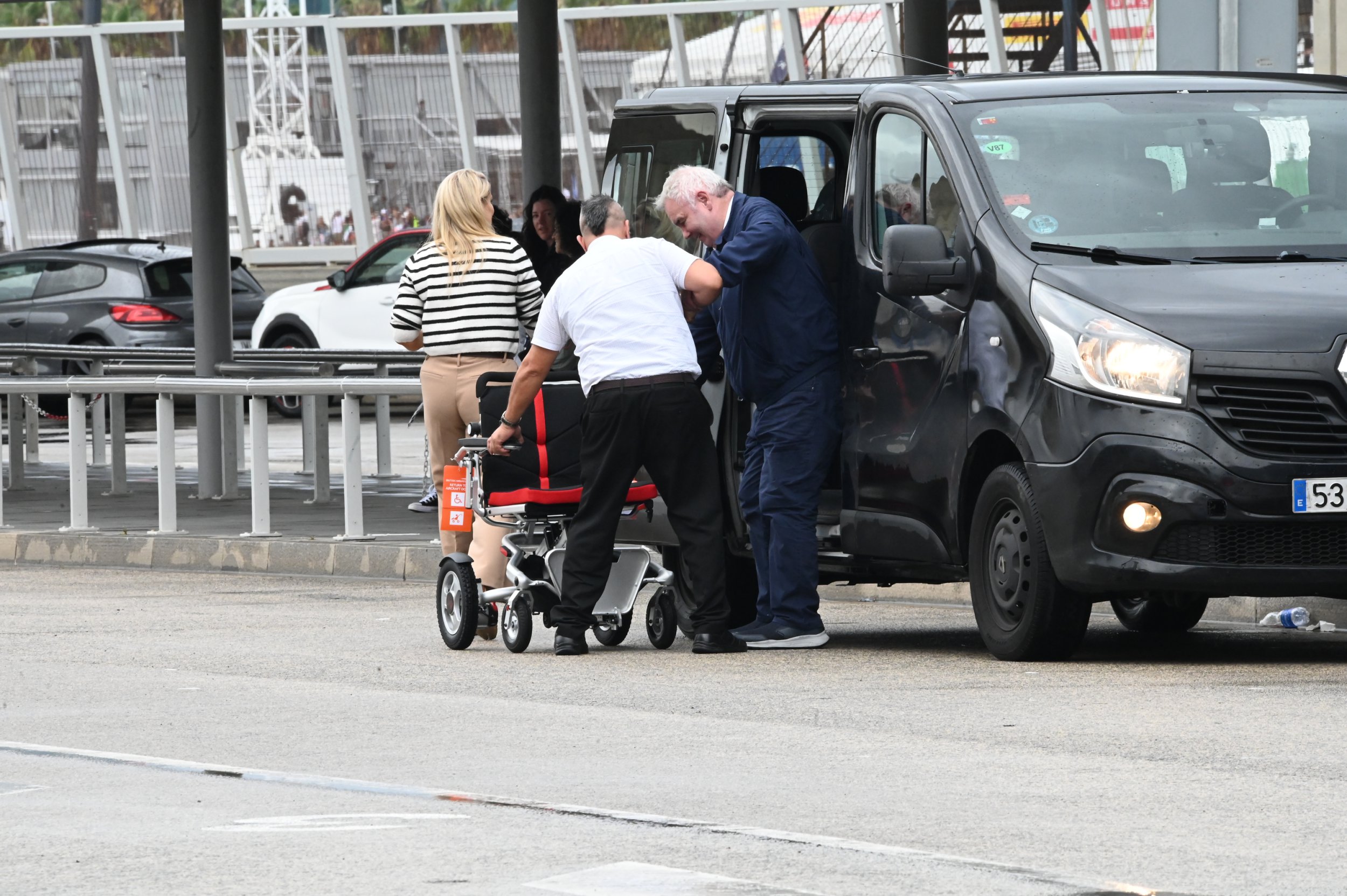 Eamonn Holmes being helped out of a car and into an wheelchair at Barcelona airport